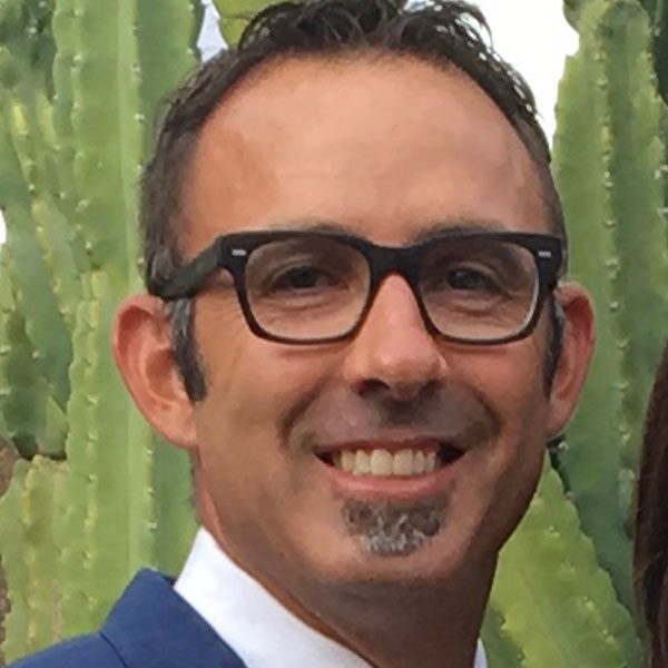 Smiling man with glasses in front of a cactus.