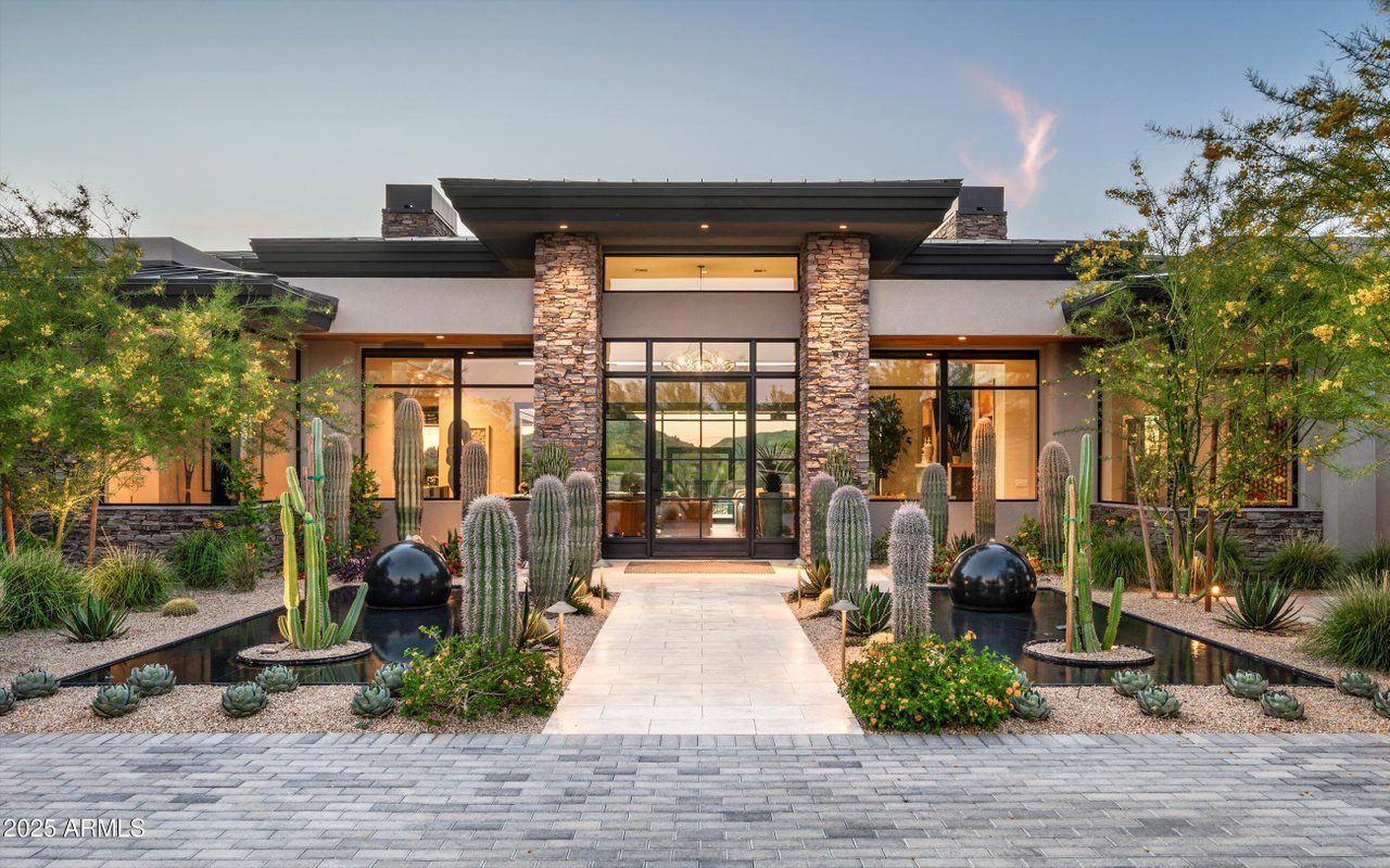 Modern house entrance with stone pillars and desert landscaping.
