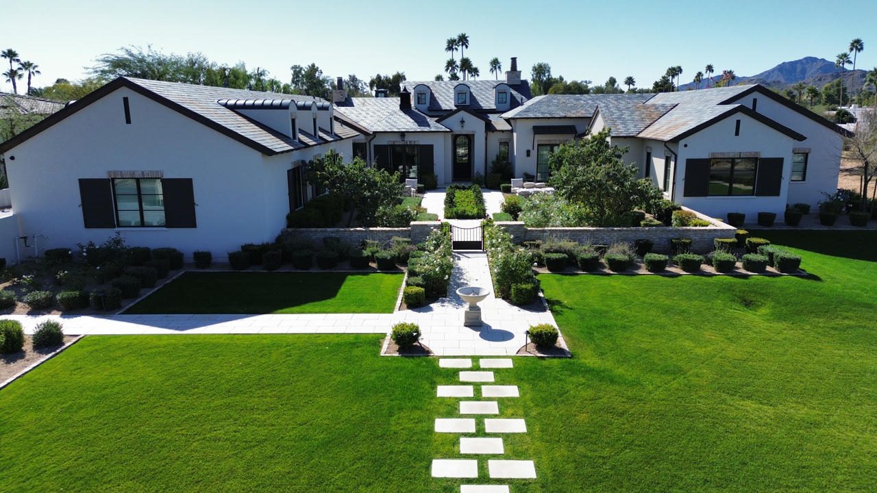 A modern white house with a manicured lawn and stone path.
