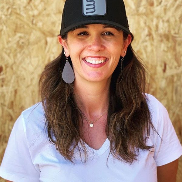 Smiling woman wearing a black cap and white shirt.