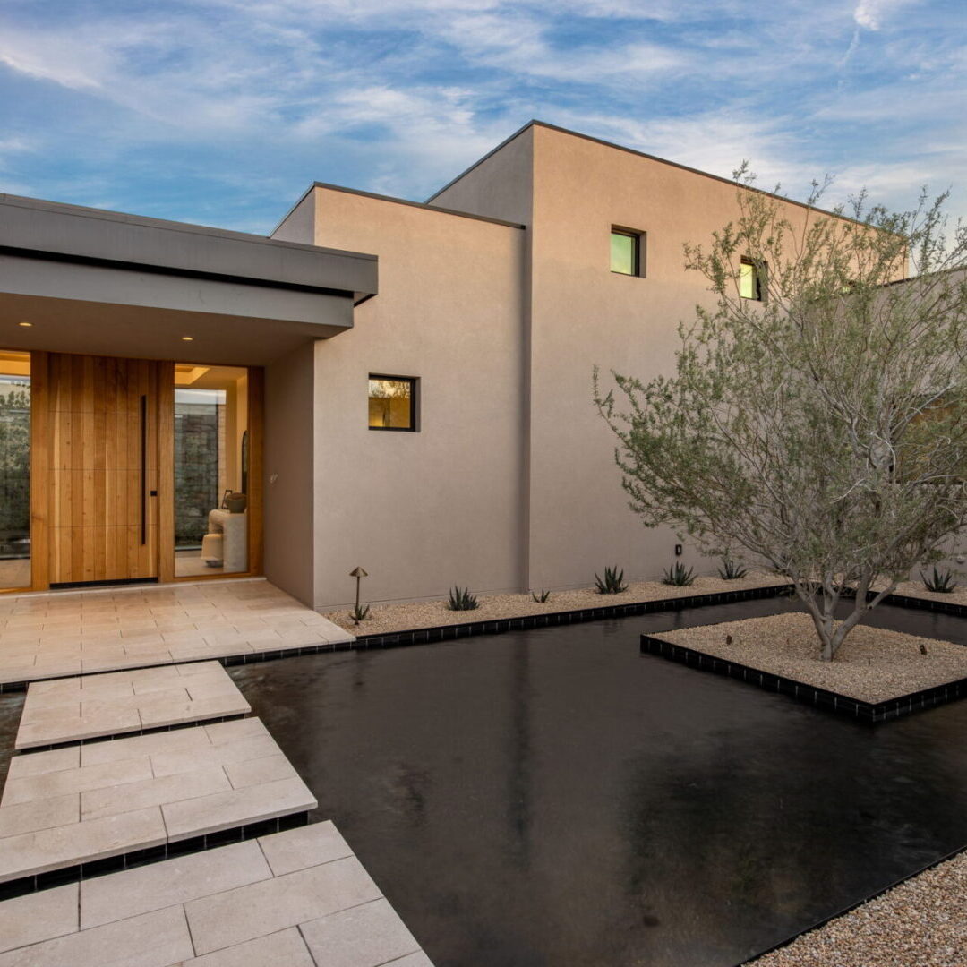 Modern house entrance with a reflective water feature and olive tree.