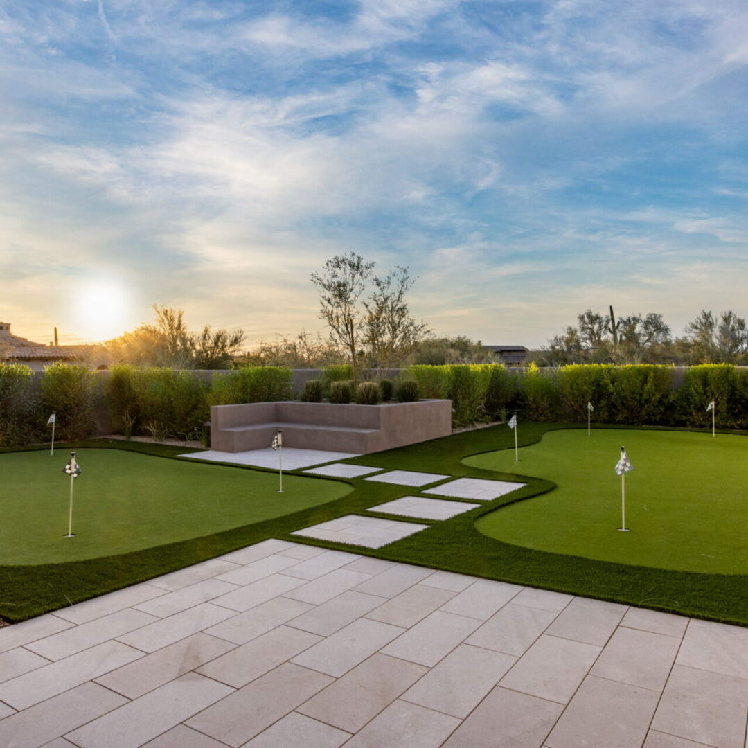 Beautiful backyard putting green at sunset with stone pathway.